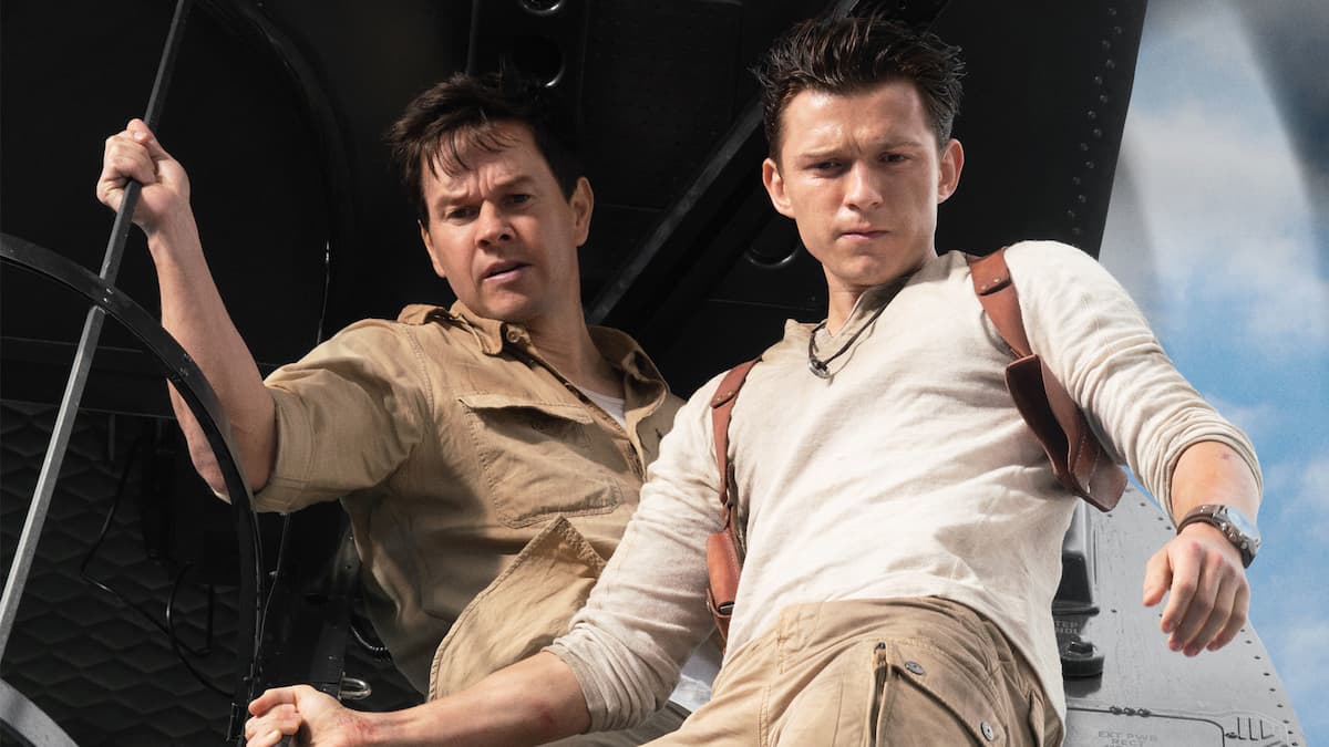 Tom Holland as Nathan Drake and Mark Whalberg as Victor Sullivan stand looking down at something.