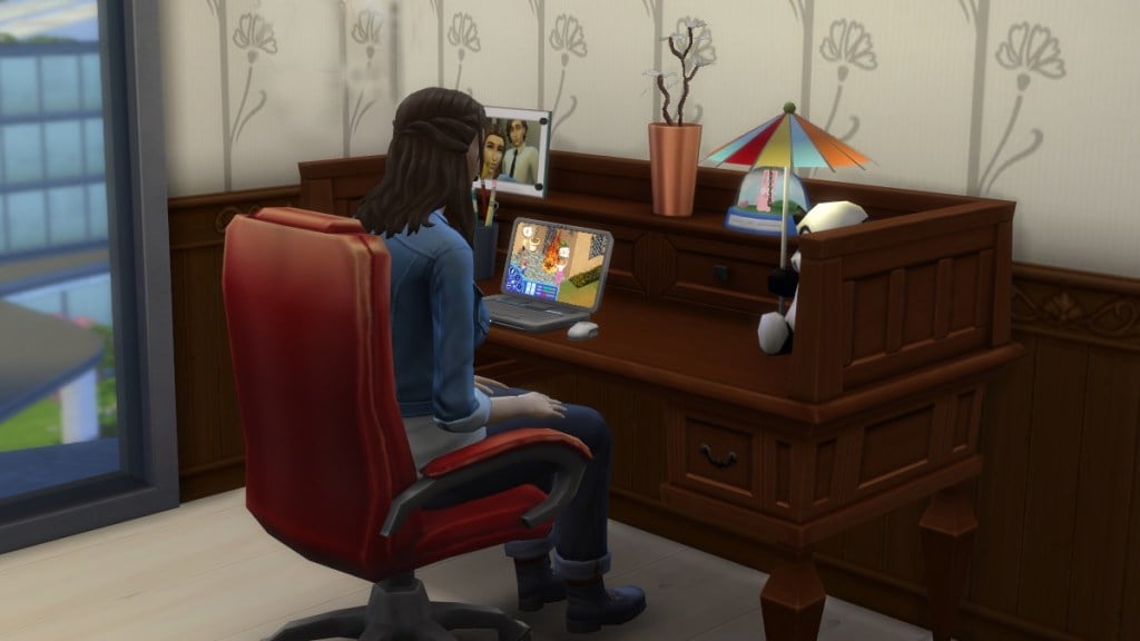 A female presenting Sim sits at a desk and plays The Sims, setting a fire in the game-within-a-game.