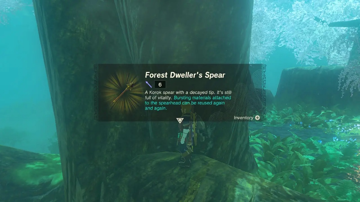 Link retrieves the forest dweller's spear from where it rests against the trunk of a tree. A pop up gives the name and full description of the spear. Text reads: Forest Dweller's Spear. 6. A Korok spear with a decayed tip, it's still full of vitality. Bursting materials attached to the spearhead can be reused again and again.