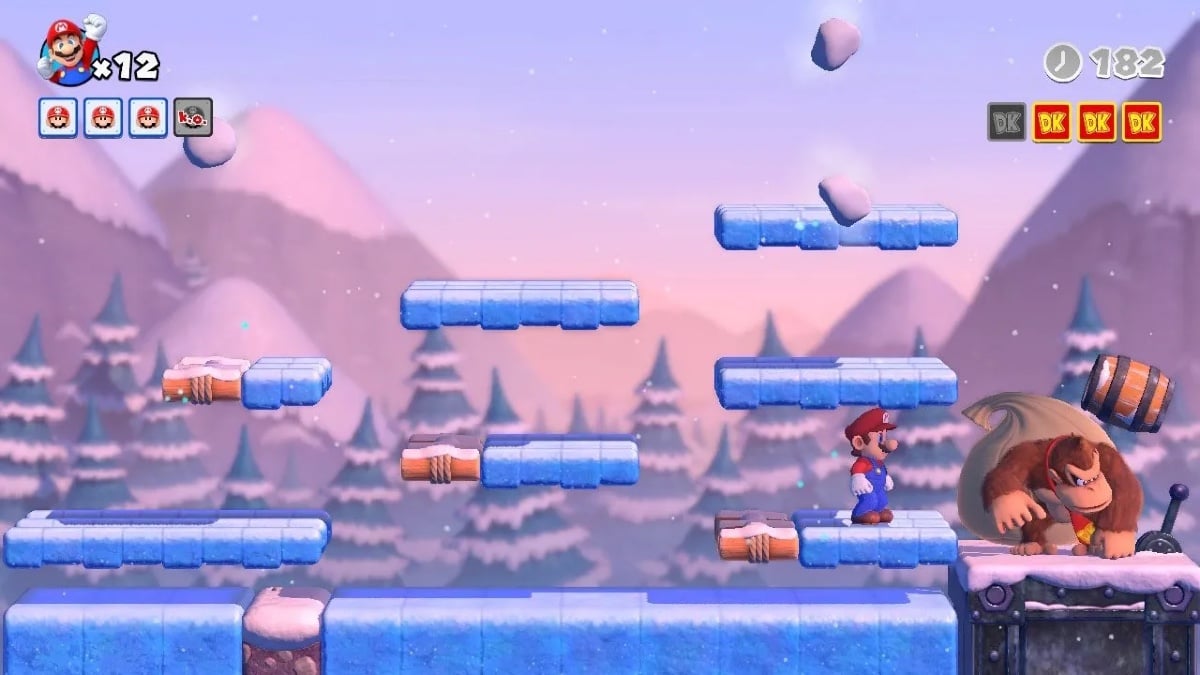 Mario closes the gap and gains ground on Donkey Kong, who is about to be hit with a falling barrel. The floating platforms look like blocks of ice and the background features snow-covered pines and capped mountains.  